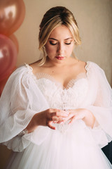 Beautiful bride puts on a ring at the bride’s gatherings, a wedding dress