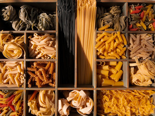 Italian pasta. Colorful pasta of various shapes lie on a wooden background. The concept of Italian pasta