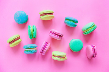 Obraz na płótnie Canvas Sweet almond colorful pink blue yellow green macaron or macaroon dessert cake isolated on trendy pink pastel background. French sweet cookie. Minimal food bakery concept. Flat lay top view copy space.