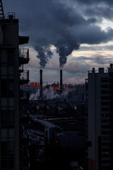 Environmental and air pollution, ecological problems concept. Smoke from factory chimneys against a gray cloudy sky. Urban landscape.