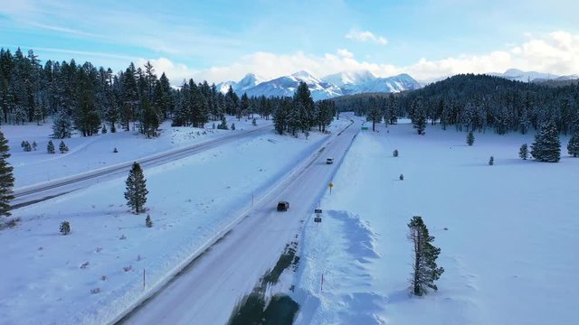 2020 - aerial of cars driving slowly on icy snow covered mountain road in the Eastern Sierra Nevada mountains near Mammoth California.