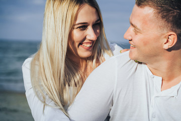 Obraz premium Lifestyle romantic evening for two. Young lovers went on a trip to the sea. Sitting on the sand in the evening sun and hugging, talking, kissing and enjoying the absence of people around.