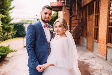 Portrait of a wedding couple of the bride and groom in a beautiful suit and dress, floral bouquet in an incredible place, horizontal photo