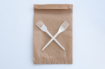 Stop using plastic. Plastic waste concept. Brown ecological paper bag and crossed plastic forks on it. Concept of Recycling plastic and ecology problem. Top view, flat lay