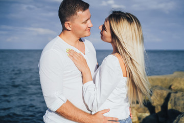 Obraz premium Loving couple having fun - they laugh, hug each other and enjoy warm summer evening. A romantic couple stands on the seashore in the golden rays of the sun and spends time together, enjoying deserts