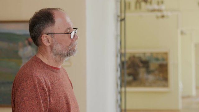 Intelligent man in the Museum for the exhibition examines paintings