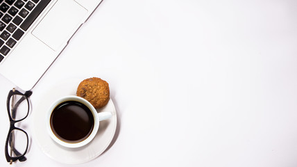 gray laptop with a cup of coffee and glasses on white background table, working place at home or in office