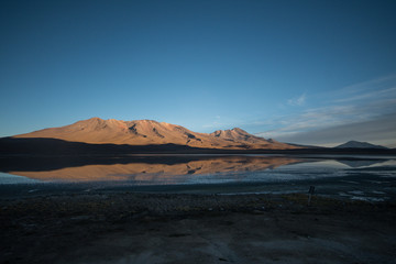 Fototapeta na wymiar Panorama of Andean peaks reflecting in laguna during sunset with bright blue sky