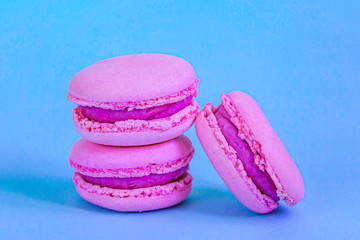 Sweet almond colorful unicorn pink macaron or macaroon dessert cake isolated on trendy blue pastel background. French sweet cookie. Minimal food bakery concept.