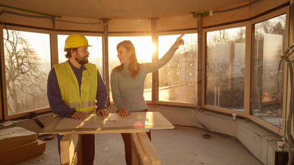 Beautiful woman and worker look around the room while analysing the floor plans