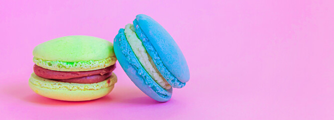 Sweet almond colorful unicorn blue yellow macaron or macaroon dessert cake isolated on trendy pink pastel background. French sweet cookie. Minimal food bakery concept. Copy space, banner