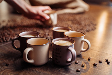 A coffee bag and  coffee beans lying on a wooden floor. There is brown cup with espresso.