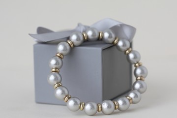a female bracelet made of Japanese cotton in gray and silver on the background of a gift box