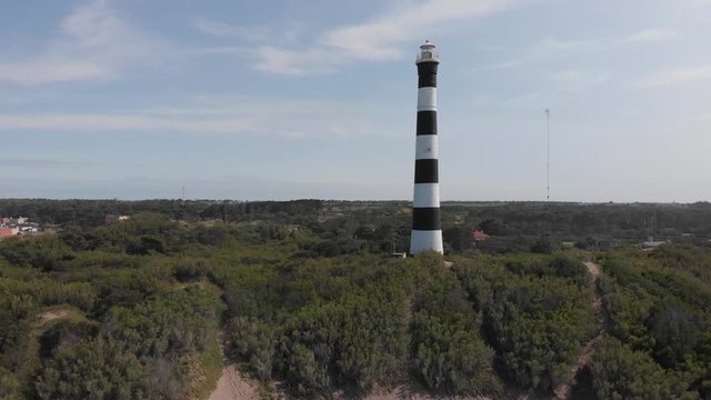 Aerial view of a lighthouse near the sea. Trees and vegetation around it