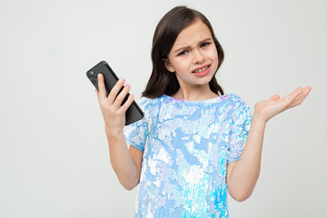 surprised teenager girl indignantly holds the phone on a white studio background