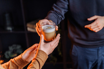 Close up of hands with coffee. Barman giving a freshly brewed, fragrant cappuccino with high milk...