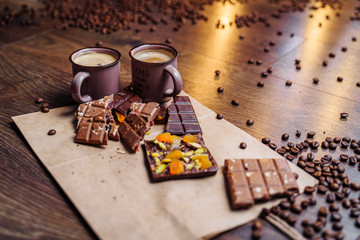Two cups of espresso coffee with grains, craft bag and chocolate on a wooden table on a dark background. Top wiev.