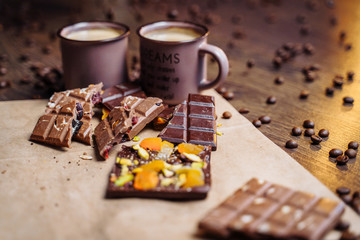 Two cups of espresso coffee with grains, craft bag and chocolate on a wooden table on a dark background. Top wiev.