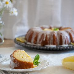 Lemon Ricotta Bundt Cake with icing displayed on a black decorative plate in a light bright airy setting.