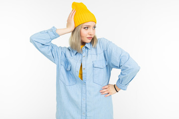 cool caucasian blond girl in a blue shirt and yellow sweater posing on a white background