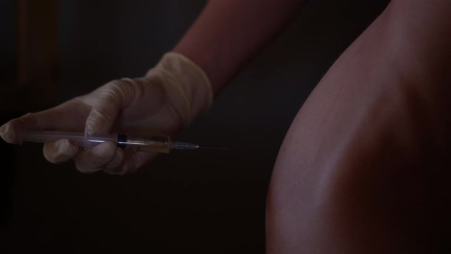 Injection for buttocks. Antibiotics self-injection at home. Woman hands holding needle.