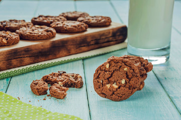 Chocolate cookies with a glass of milk on the light green wooden table