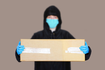 Delivery of goods during quarantine. Delivery employee delivering cardboard box. Courier in medical gloves and mask