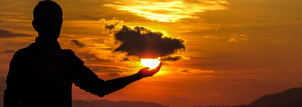 Optical Illusion Of Silhouette Man Holding Sun During Sunset