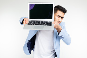 smiling young brunette man joyfully holds a laptop with blank for inserting a website page on a white background