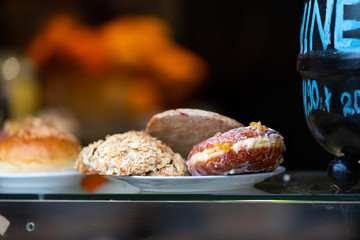 Cafe or restaurant street window display in old town market square Warsaw, Poland with doughnuts donut, slivered almonds bread pastry on plate in Christmas