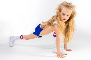 young little blonde girl is stretching on a white background