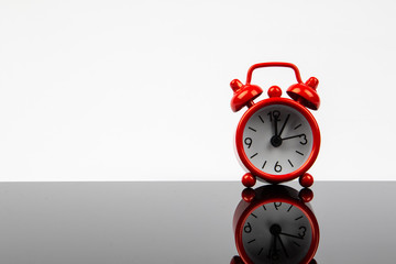 Red retro alarm clock with reflection on a white background