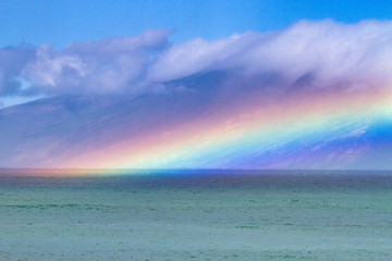 Electric rainbow hovering over the ocean on Maui.