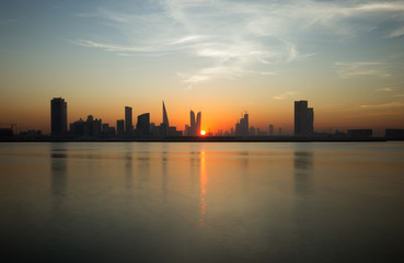 Obraz premium Beautiful sun in the mid of Bahrain skyline during sunset