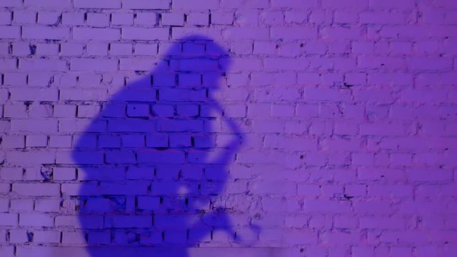Silhouette of a woman playing the saxophone on a purple brick wall. Background for text with saxophonist copy space