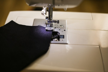 Sewing machine and black pattern fabric face mask. Sewing a mask on a typewriter during a pandemic.