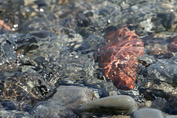 Stones, pebbles on the seashore, partially covered with water