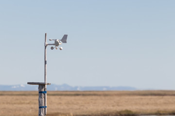 Home weather station is tied with tape to a stick, against the background of the tundra and mountains on the horizon