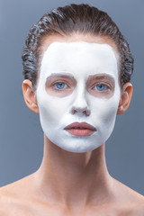 Beautiful girl is applied a white cosmetic mask from black dots. Isolate, studio.