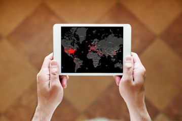 a man holding a tablet in his hands with a distribution map of coronavirus or covid-19, standing at home near the window, top view