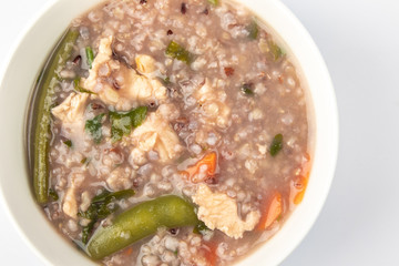 Delicious homemade brown rice porridge with few slice chicken, carrot and vegetable isolated on white background.  