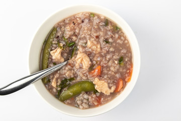 Delicious homemade brown rice porridge with few slice chicken, carrot and vegetable isolated on white background.  