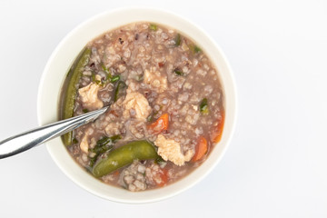 Delicious homemade brown rice porridge with few slice chicken, carrot and vegetable isolated on white background.  