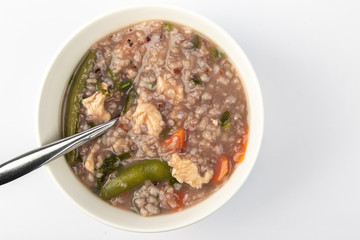 Delicious homemade brown rice porridge with few slice chicken, carrot and vegetable isolated on white background.  