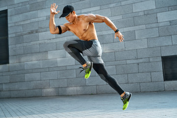 Sporty man running. Side view of active man training in the city. Dynamic movement. Sports and...