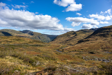 Fototapeta na wymiar Norway sunny autumn panoramic view on mountains plateau with vibrant blue sky with clouds, epic trip to scandinavia