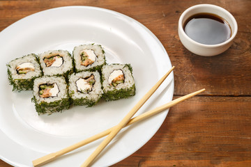 Rolls with salmon and dill on a white plate and soy sauce.