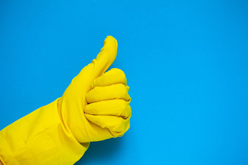 Closeup of hand in yellow mittens holding cleaning supplies.