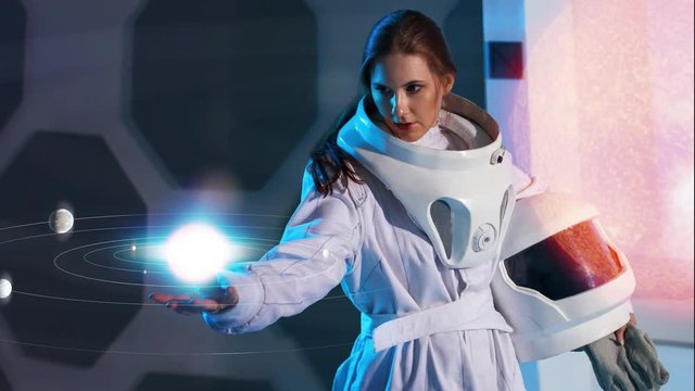 Portrait of a young female space Explorer in a futuristic space suit. An astronaut holds a hologram of an unknown planetary system on hand, searching for a new earth, colonization
