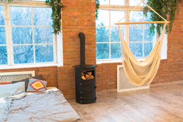 loft style bedroom with brick wall with hammock and wood heater,design interior